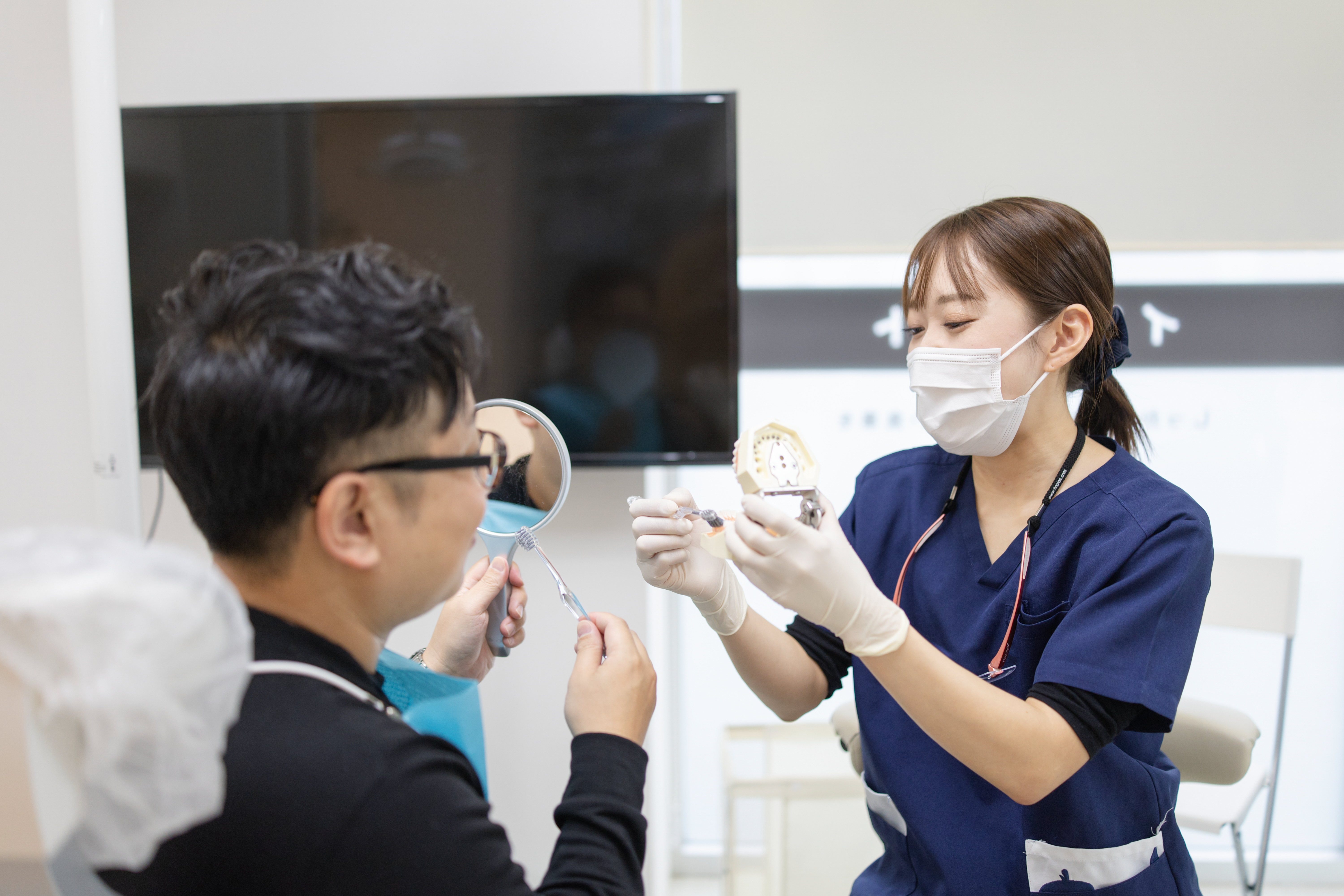 歯科衛生士が歯の模型を使って患者にブラッシング方法を指導する様子